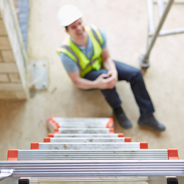 worker holding knee in pain at the bottom of ladder